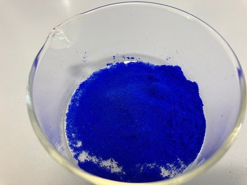 Ein blaues Pulver in einem Glasgefäß.